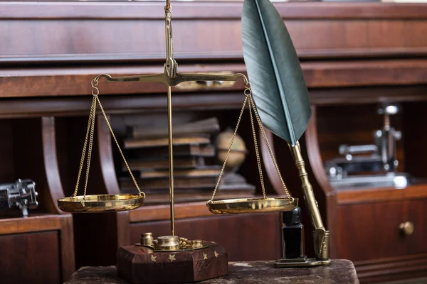 Κλίμακα της δικαιοσύνης με νομικά βιβλία στο τραπέζι του συμβολαιογράφου στο γραφείο. — Φωτογραφία Αρχείου