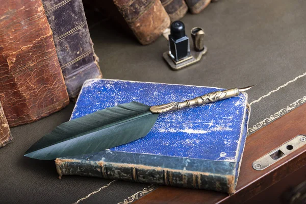 Eski kitapların ahşap masada toplanması ve kalem yazılması.