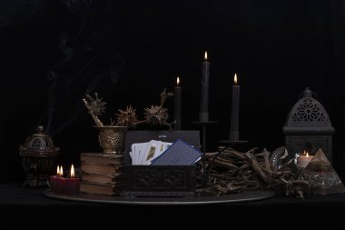 Tarot kartı doğa gösterisinde sergileniyor. Kurutulmuş bitkilerle, mavi çiçeklerle, beyaz mumlarla çevrili koyu ahşap bir masada el yapımı tarot kartları. Mavi kartlar.