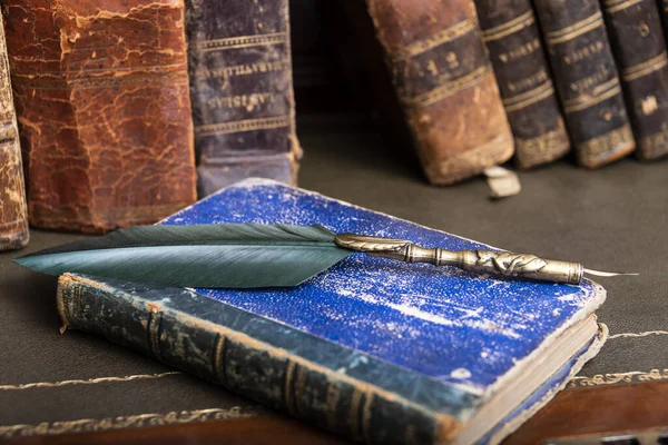 Ancienne plume, livres et encrier vintage sur un bureau en bois dans l'ancien bureau sur fond de bibliothèque et de rayons de lumière. Contexte conceptuel sur l'histoire, l'éducation, la littérature . — Photo
