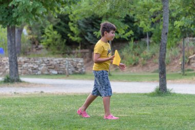 Mutlu çocuk gün batımında gökyüzüne karşı oyuncak uçakla oynuyor.