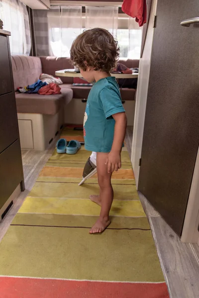 Cute and diligent baby cleans the caravan with a vacuum cleaner