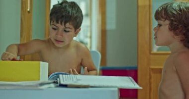 two kids doing homework back to class shirtless because of the heat