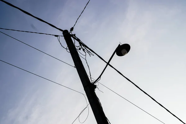 Silhouette of tall street light pole with cable structure