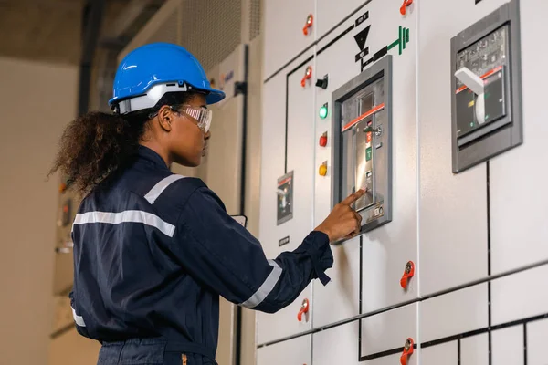 Professional engineer black women working with tablet at warehouse factory. Engineer Worker Wearing Safety Uniform and Hard Hat. Female  checking at electrical cabinet control.