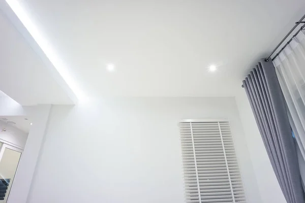 LED strip light and illumination. Also called ribbon light or LED tape to suspended on ceiling in plasterboard in empty living room include down light, white wall. Interior home design and technology.