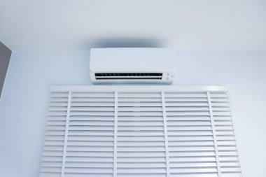 İklimi, sıcaklığı ve nemi kontrol etmek için havalandırma (ac) duvar montajı veya bölme sisteminin iç ünitesi. Doğal ışığı iç odaya ayarlamak için dikey ya da venedik jaluzileri de dahil et.