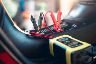 Charging electric power, energy to accumulator or dead battery in breakdown motorcycle or motorbike for start. Include equipment tool i.e. portable trickle charger, positive negative clamp, red black cable wire. May called recharge, check, repair.