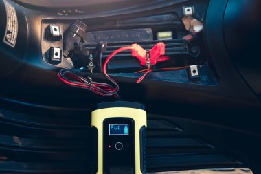 Charging electric power, energy to accumulator or dead battery in breakdown motorcycle or motorbike for start. Include equipment tool i.e. portable trickle charger, positive negative clamp, red black cable wire. May called recharge, check, repair.
