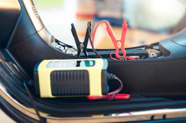 Charging electric power, energy to accumulator or dead battery in breakdown motorcycle or motorbike for start. Include equipment tool i.e. portable trickle charger, positive negative clamp, red black cable wire. May called recharge, check, repair.
