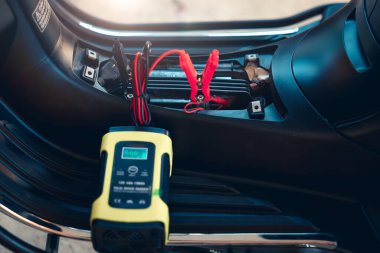 Elektrik, akümülatöre enerji, motorsiklet arızası ya da motorsiklette şarj oluyor. Ekipman aracını dahil et Taşınabilir şarj aleti, pozitif negatif klemp, kırmızı siyah kablo. May aradı, şarj et, kontrol et, onar.