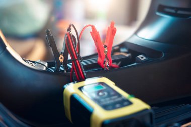 Charging electric power, energy to accumulator or dead battery in breakdown motorcycle or motorbike for start. Include equipment tool i.e. portable trickle charger, positive negative clamp, red black cable wire. May called recharge, check, repair.