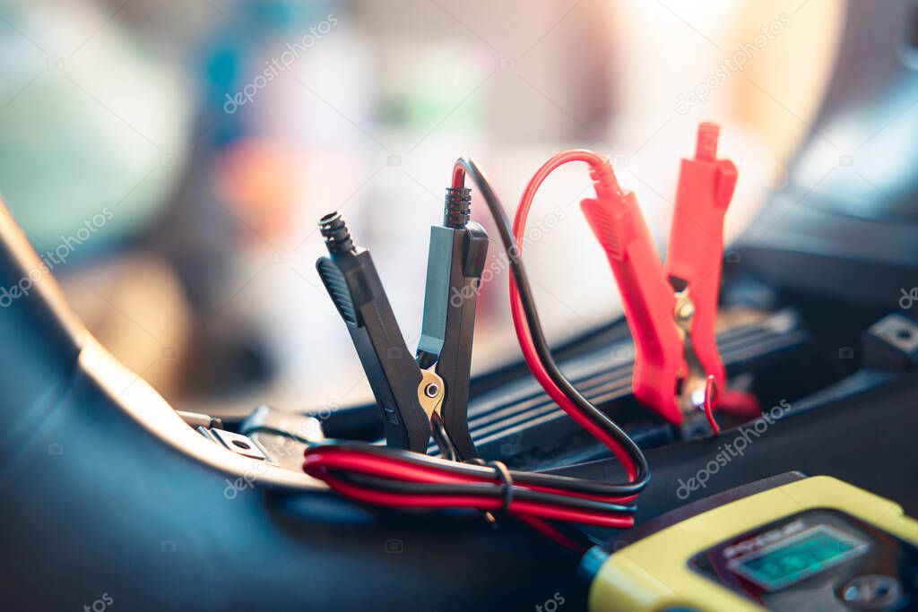 Charging electric power, energy to accumulator or dead battery in breakdown motorcycle or motorbike for start. Include equipment tool i.e. portable trickle charger, positive negative clamp, red black cable wire. May called recharge, check, repair.