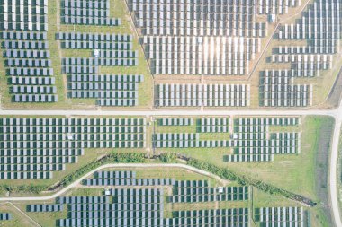 Hava görüntüsündeki güneş çiftliği, alan veya güneş enerjisi santrali panel, manzara ve teknoloji içindeki fotovoltaik hücreden oluşur. Elektrik endüstrisi, elektrik üretimi güneş ışığı veya güneş ışığı ile üretiliyor. Temiz ve yeşil güç, doğadan gelen sürdürülebilir enerji..