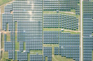 Hava görüntüsündeki güneş çiftliği, alan veya güneş enerjisi santrali panel, manzara ve teknoloji içindeki fotovoltaik hücreden oluşur. Elektrik endüstrisi, elektrik üretimi güneş ışığı veya güneş ışığı ile üretiliyor. Temiz ve yeşil güç, doğadan gelen sürdürülebilir enerji..