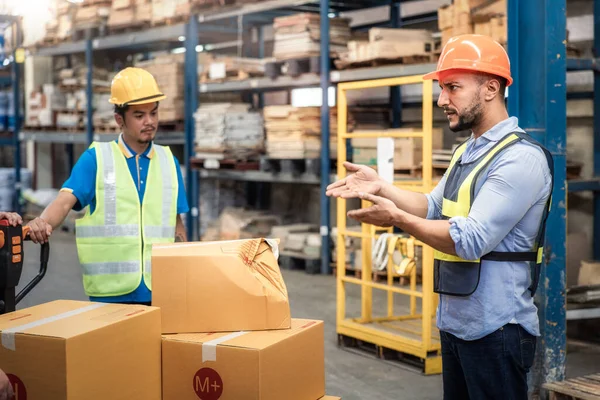 Supervisor, manager or boss to angry, scold or mad to worker, employee inside distribution warehouse about bad, damage, broken or dented of cardboard box package. May called carton, parcel, cargo.