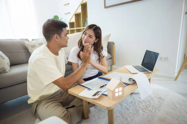 Asian couple in home or house. To compare prices, interest, credit. Include laptop, calculator and document on table. Concept for marriage, loan, finance, insurance, mortgage, real estate and property