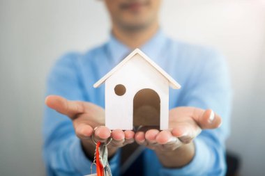 İş adamı, temsilci ya da komisyoncu. Ev, ev ya da konut modelini elinde tutmak ve satış, kira, satın alma ve yatırım yapmayı teklif etmek. İş, gayrimenkul, mülk kavramı.