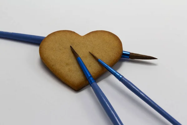 Biscuits en forme de coeur sur fond blanc avec pinceaux bleus, décoration alimentaire, Art pâtissier, décoration de biscuits, horizontal, espace de copie — Photo
