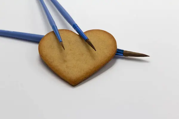 Biscuits en forme de coeur sur fond blanc avec pinceaux bleus, décoration alimentaire, Art pâtissier, décoration de biscuits, horizontal, espace de copie — Photo