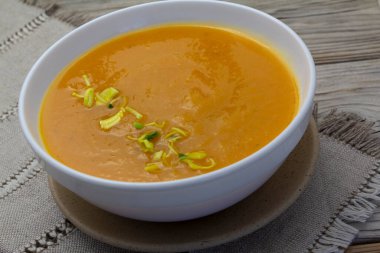 Ahşap arka planda beyaz kasede kalın ve kremalı balkabağı çorbası, keten peçete. Sağlıklı beslenme