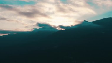 Dağlarda güzel bir gün batımı. Güneş ışınları bulutlar arasında parlıyor.