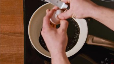 Erkek eli siyah yağda yumurtayı kızartma tavasına kırar. Kara yağda kızartılmış yumurta, filtresiz petrol ürünlerine benzer. Kaynayan siyah yağ çerçevesi 100 fps 'ten 2.8 km yukarıdan.