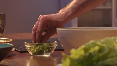 Adamın biri maydanozla doğranmış soğan döker ve salatanın içine dereotu döker. Bir adam kendine sağlıklı bir akşam yemeği pişirir. sağlıklı diyet yemekleri. Bir sürü vitaminle yemek pişirmek 100 fps 2.8 bin.