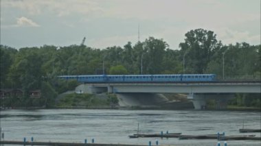 Ukrayna 'nın başkenti Kyiv' de nehrin üzerindeki köprüde farklı yönlere giden iki metro treni. Metro Köprüsü yaz öğleden sonra. Yavaş Hareket 100fps 2.8k