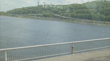 Kyiv 'in sağ kıyısındaki metro manzarası. Ukrayna bayrağına kadar uzanan panorama ve Dnipro nehrinin karşısındaki anavatanın anı. Kyiv 'i görüyorum. Yavaş Hareket 100fps 2.8k