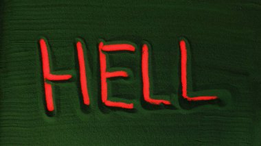 Yeşil Kum 'daki Cehennem Kelimesi' ni elle çizmek. Erkek el yeşil kumun üzerine kırmızı ışıkla Cehennem kelimesini yazar. Üst görünüm 4k çözünürlüğü