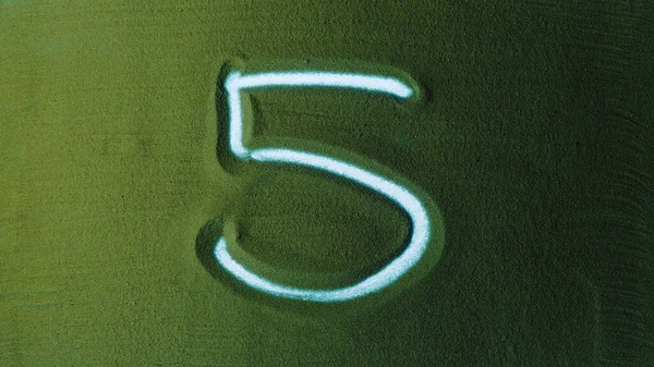 手绘五号五号标志在绿沙中 男性用背光在绿色沙滩上写下一个数字 这是一个从0到10的系列 顶视图4K分辨率 — 图库照片