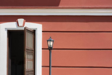 Kahverengi demir kapı, bahçe lambası ve fayans kırmızı duvar.