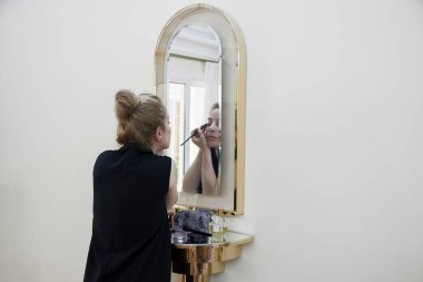 Genç bir kadın aynanın önünde makyaj yapıyor. Önemli bir güne hazırlanıyorum.