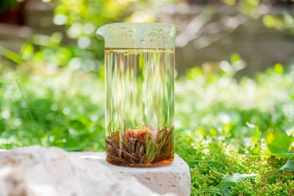 Bahçede limon ve taze nane yapraklarıyla servis edilen bir taşın üzerinde çiçek açmış çay duruyor. Seçmeli Odak Camı