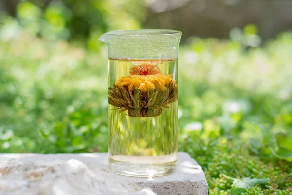 Bahçede limon ve taze nane yapraklarıyla servis edilen bir taşın üzerinde çiçek açmış çay duruyor. Seçmeli Odak Camı