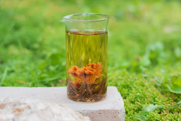 Bahçede limon ve taze nane yapraklarıyla servis edilen bir taşın üzerinde çiçek açmış çay duruyor. Seçmeli Odak Camı