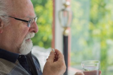 Gözlüklü kel yaşlı adam günlük ilaçlarını alıyor. Seçici Odak Adam