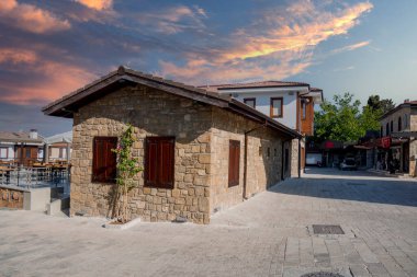 Şehir merkezinin caddeleri, çarşı ve Antalya 'daki liman bölgesi. Sokak manzaralı. Gün batımı bulutlu gökyüzü. Kafe, restoran, dükkan ve evler. İnsan yok. Seçici odaklanma.