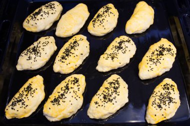 Yumurta sarısı ile fırçalanmış ve siyah kimyon serpiştirilmiş ev yapımı hamur işleri. Seçici odaklanma. Fırın tepsisinde.