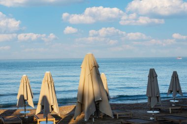 Deniz, sahil, şemsiyeler ve Antalya tarafındaki güneş pansiyonları. Bulutlu bir gökyüzü. Seçici Odaklanma. İnsan Yok.