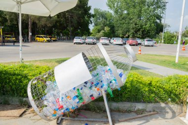 İçinde plastik şişe olan demir bir çöp tenekesi..