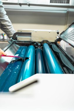 Renkli ve parlak baskı makinesi silindirleri. Değişken mürekkep rengi. Mavi. Fotoğraf dikey, seçili odak silindiri ortada.