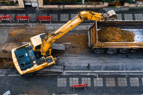 建筑设备挖掘城市街道以改善废水基础设施 顶视图 选择性聚焦机 免版税图库照片