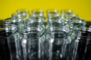 Boş cam kavanozların önü arka planda sıralanmıştı. öndeki kavanozun üzerine odaklan.