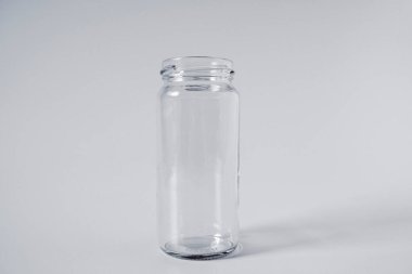 Beyaz arka planda izole edilmiş boş bir cam kavanozun yakın plan çekimi.