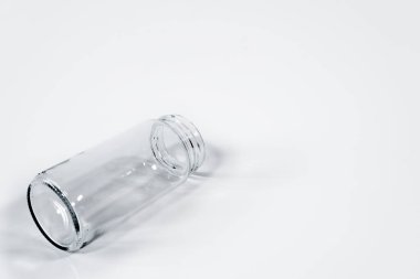 Beyaz arka planda izole edilmiş boş bir cam kavanozun yakın plan çekimi.