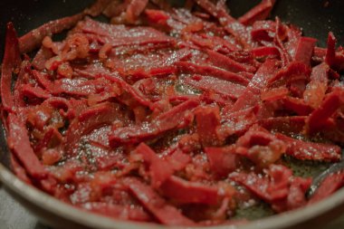 Domuz pastırması kızartma tavasında pişiriliyor. Seçici odaklı pastırma.