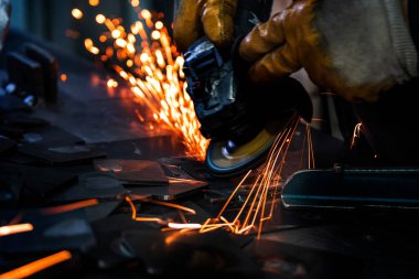Fabrikada elektrikli tekerleği olan öğütülmüş metal plakalar. Çarkın kıvılcımları. Seçici odak öğütme makinesi ve metal plakalar. Hareket bulanık kıvılcımlar