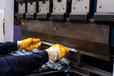 Düz metal levha için hidrolik fren ya da bükme makinesi. Bükme makinesindeki işçi bükme levhası metali.